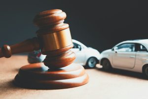a toy car and a wooden gaven on a table; car accident investigations