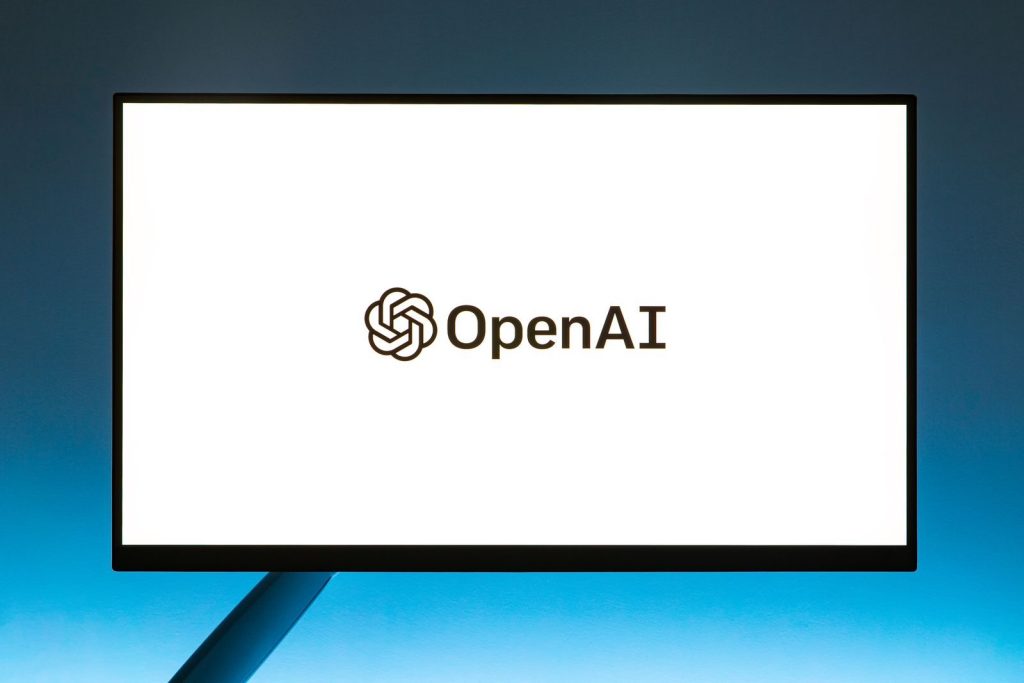 Minimalistic display of OpenAI logo on a monitor with a gradient blue background, representing modern technology.; OpenAI Dots