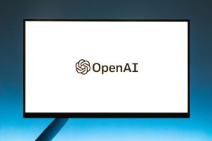 Minimalistic display of OpenAI logo on a monitor with a gradient blue background, representing modern technology.; OpenAI Dots