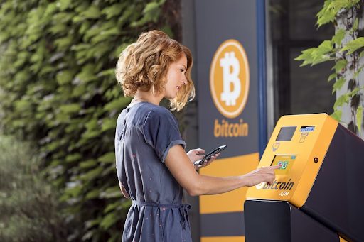a woman using a cell phone in front of a bitcoin ATM