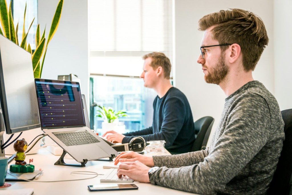 man sitting on chair wearing gray crew-neck long-sleeved shirt using Apple Magic Keyboard; co-managed IT support