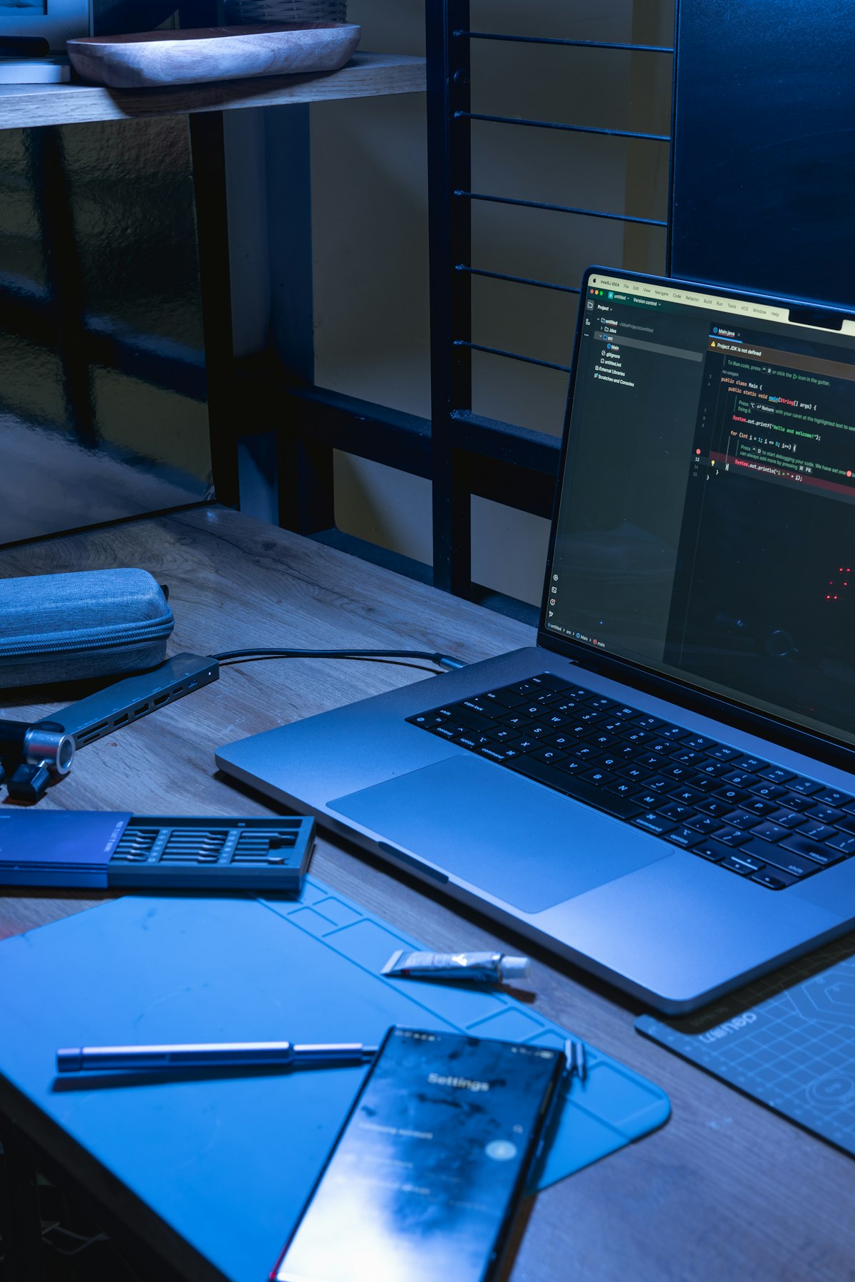 Laptop and phone on a desk with coding software open.