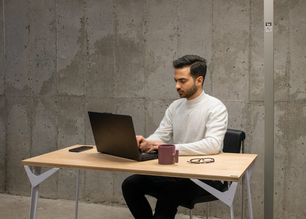 a man sitting at a table using a laptop computer; error tracking tools