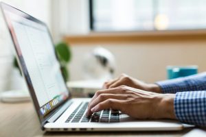 person typing on silver MacBook; npm Trusted Publishing vulnerability