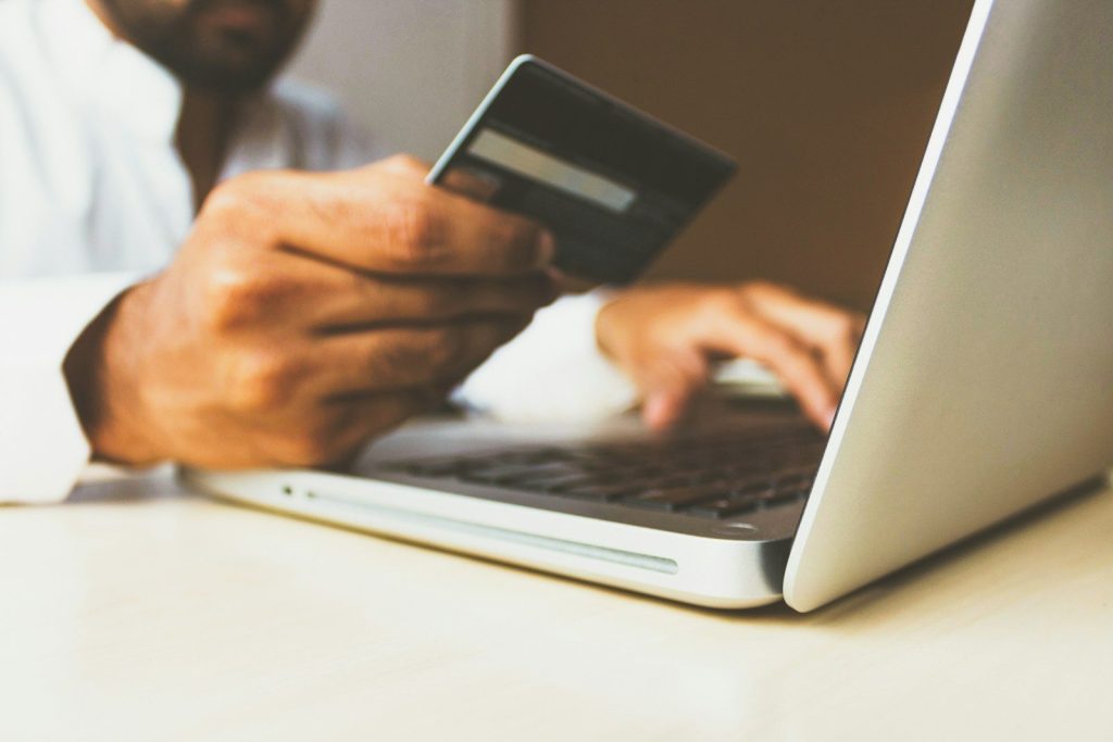person using laptop computer holding card; fintech credit repair tools
