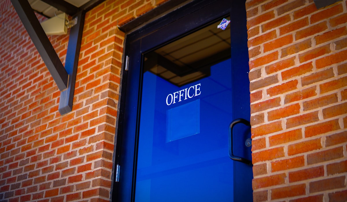 A blue office door on a brick building.