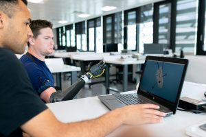 man in blue crew neck t-shirt using black laptop computer; hiring AI engineers