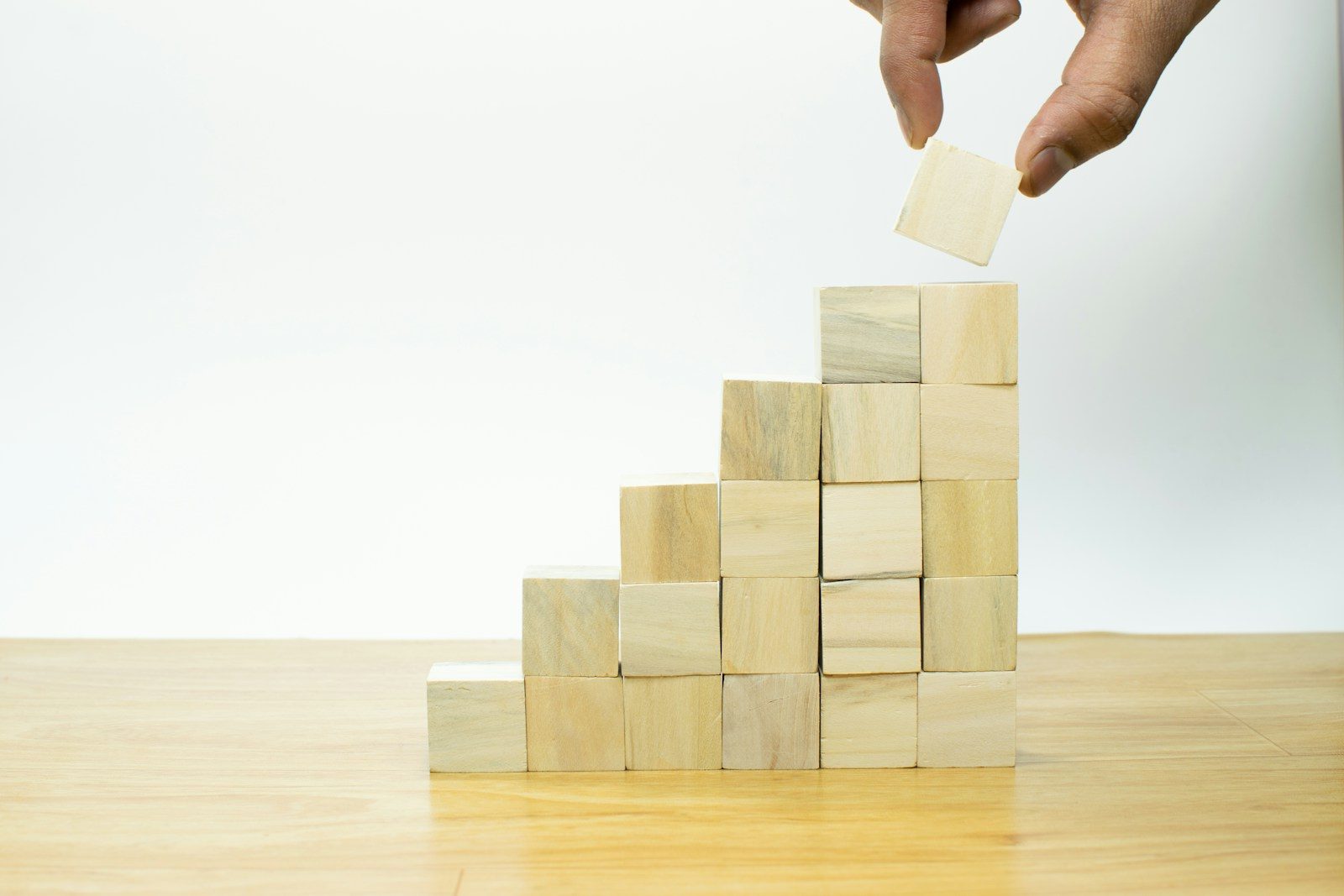 A person placing a piece of wood into a pyramid. AI for business growth
