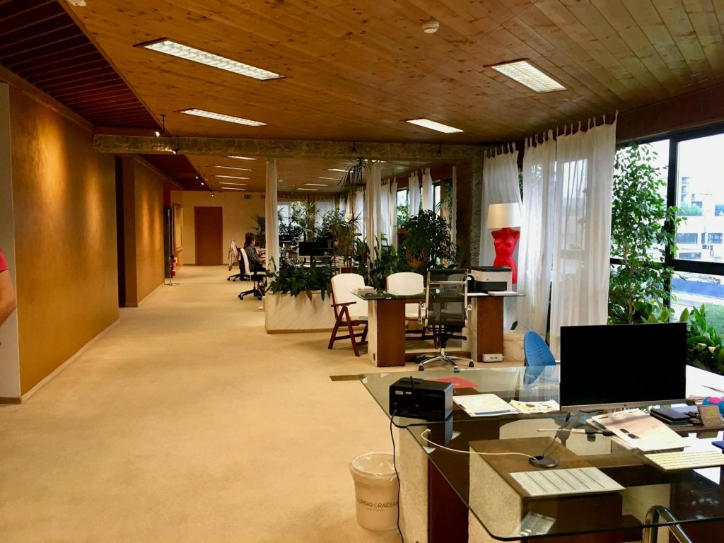 black monitor on table near printer paper on office area of the building with no people; open office